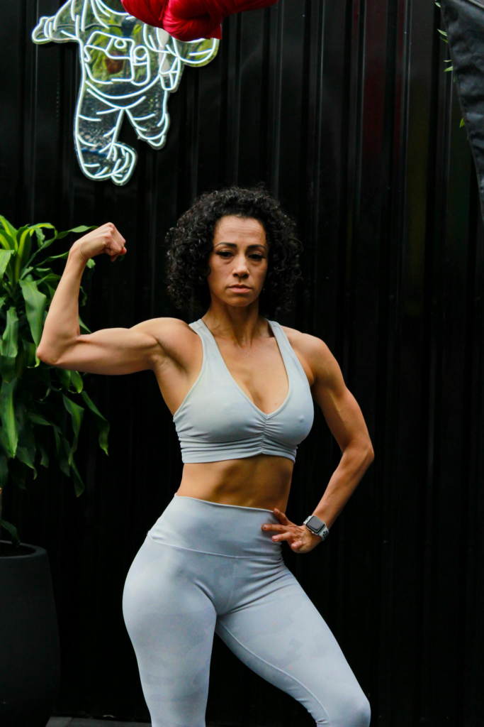 A fit woman flexing her muscles in stylish activewear, showcasing strength and confidence.