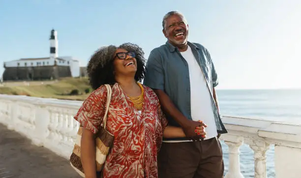 A happy and healthy elderly couple holding hands while walking along the beach