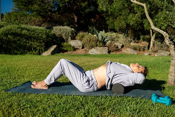 Woman over 40 practicing yoga outdoors on a sunny day